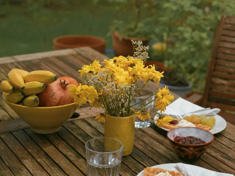 Breakfast of fruit, yoghurt and pastries on a garden table with yellow flowers