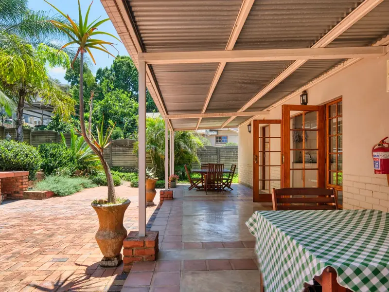 Shaded brick stoep with a garden view and a table set for breakfast